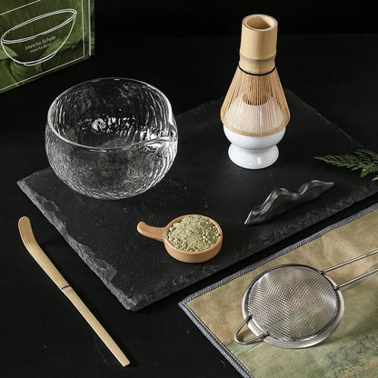 Glass matcha bowl with bamboo chasen whisk and chashaku scoop closeup