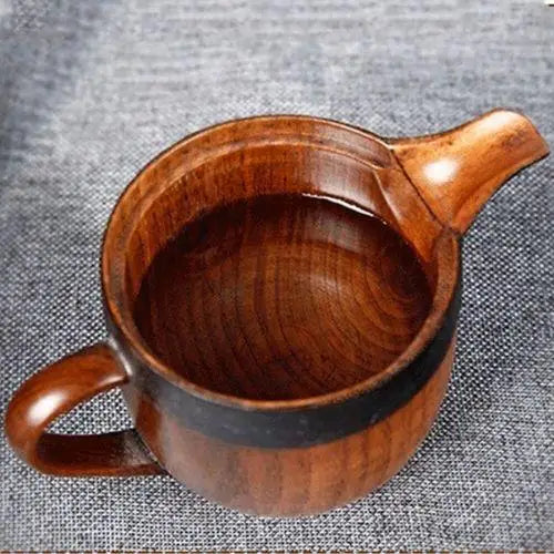 Natural wood teapot being used to pour brewed tea into cup