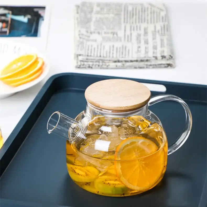 Large 1-liter borosilicate glass teapot on a wooden tray with loose leaf tea