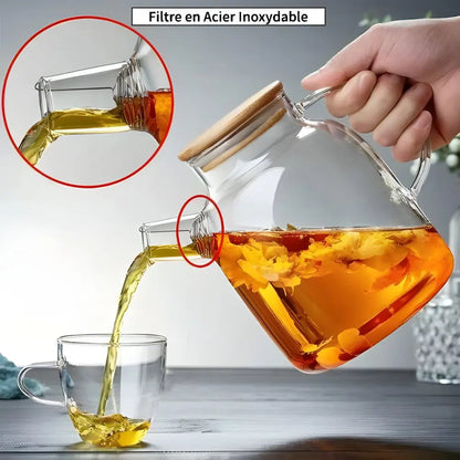 Pouring tea from large glass teapot into a ceramic cup