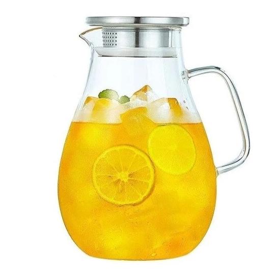 Glass teapot with infuser pouring loose leaf tea into ceramic cup