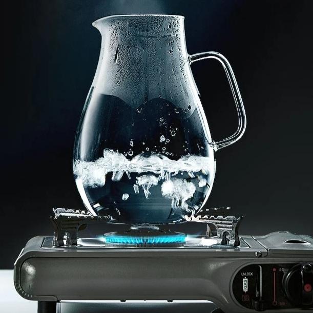 Large glass teapot with steel lid on kitchen counter, side view