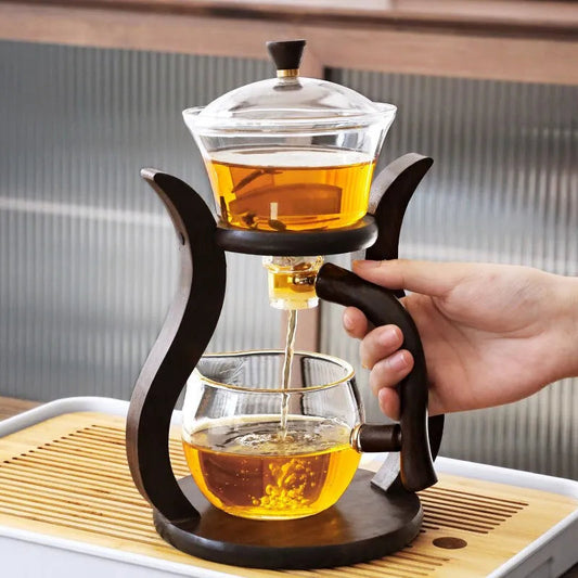 Rotating borosilicate glass teapot with infuser beside a filled tea cup
