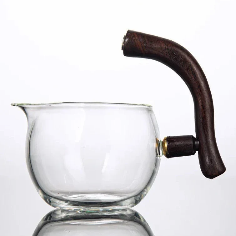 Magnetic glass teapot surrounded by loose-leaf tea and a ceramic cup