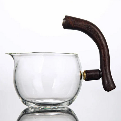 Magnetic glass teapot surrounded by loose-leaf tea and a ceramic cup