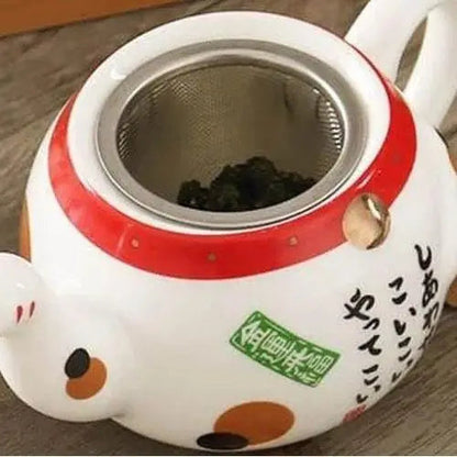 Close-up of lucky cat painted motif on white porcelain teapot