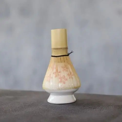 Porcelain chasen stand displaying bamboo matcha whisk upright for drying