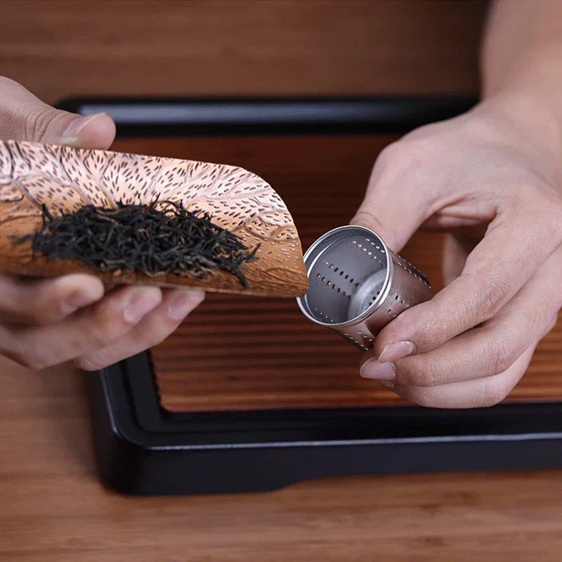 Glass tea infuser inverted to stop steeping, stainless filter visible at base
