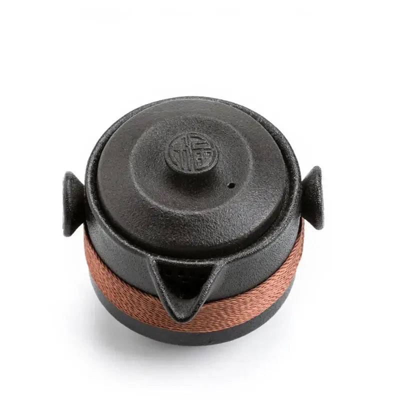 Matte black ceramic travel tea set with clean minimalist lines on neutral surface
