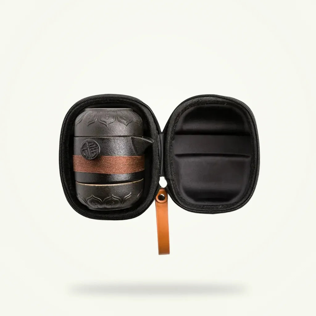 Mini nomadic tea set for travel, matte black ceramic teapot and two cups on plain background