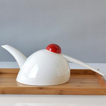 Porcelain teapot with four cups arranged on a natural wood surface
