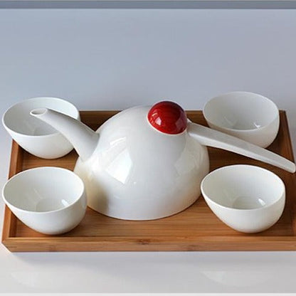 Scandinavian porcelain teapot pouring hot tea into a matching cup