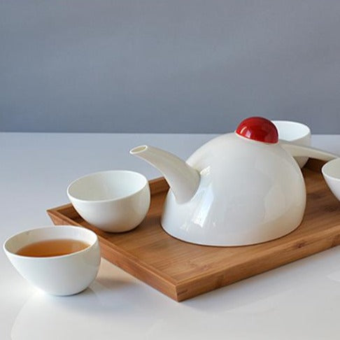 Porcelain teapot set with four cups displayed on a kitchen shelf