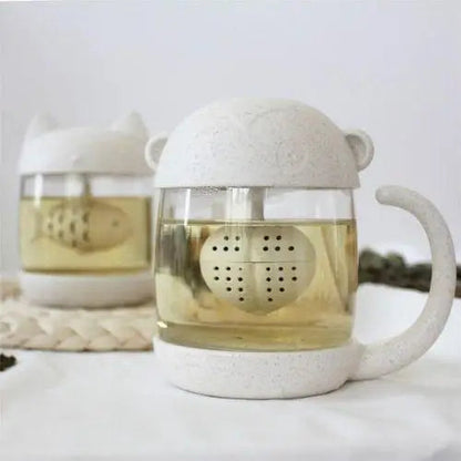 Clear glass tea cup with monkey infuser on white background
