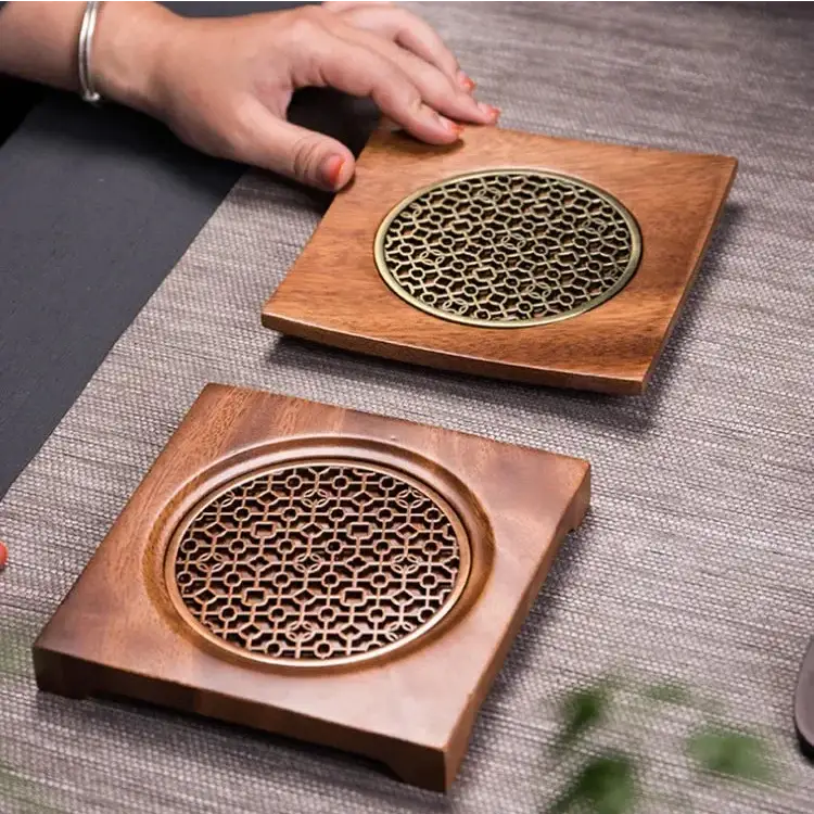 Cast iron teapot resting on natural wood trivet with decorative grid