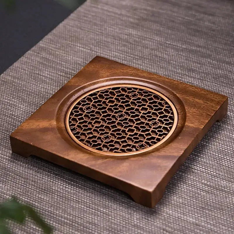 Solid wood trivet for teapot shown on light kitchen counter surface