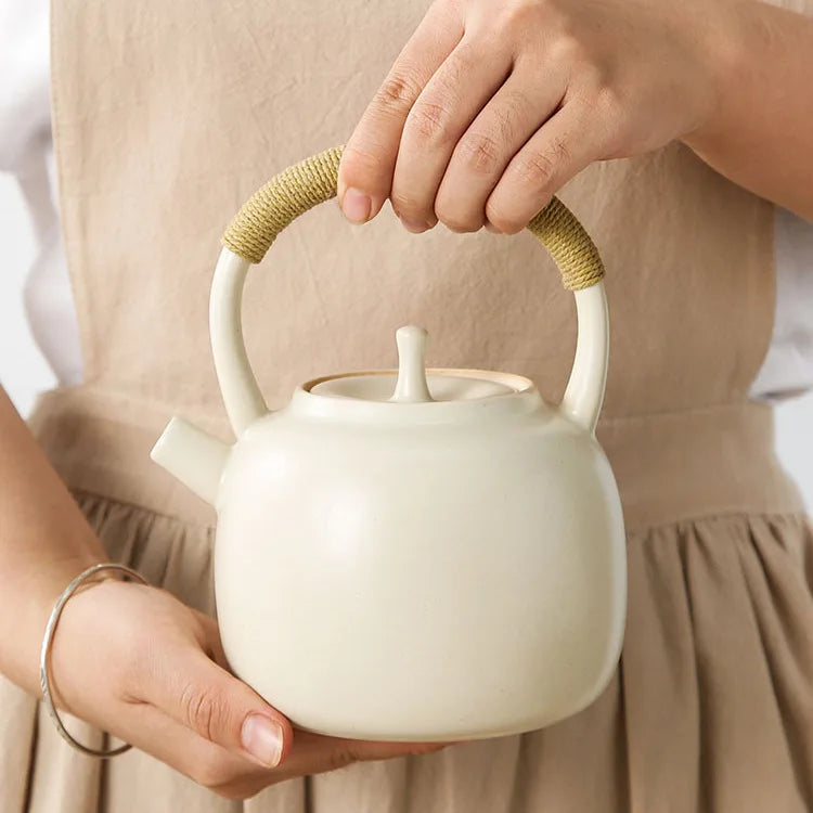 Nordic ceramic teapot pouring tea into a small ceramic cup