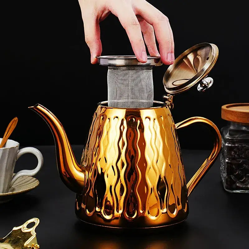Stainless steel induction teapot pouring tea into ceramic cup