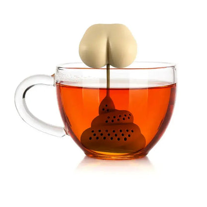 Novelty poop-shaped tea strainer resting on a white saucer beside a teacup