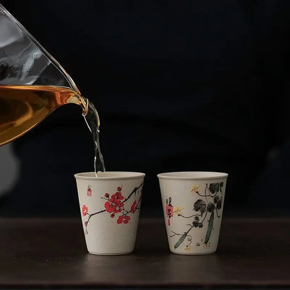Six raw ceramic tea cups arranged around illustrated wooden gift box