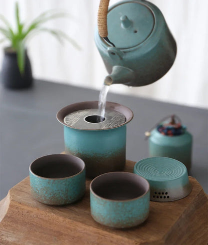 Two matching green ceramic teacups next to rustic teapot