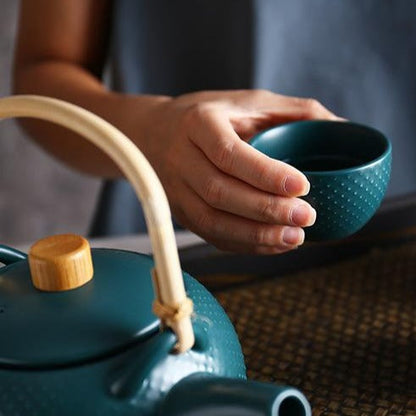 Ceramic teapot with cup and tea in background