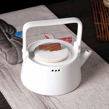 Scandinavian ceramic teapot pouring loose-leaf tea into ceramic cup