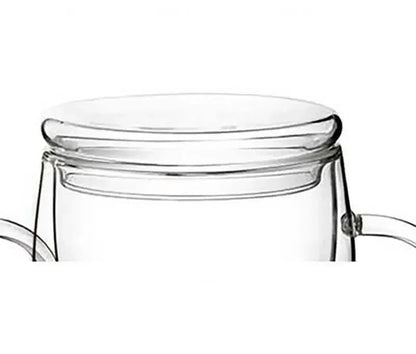 Double wall glass teapot with bamboo lid pouring hot tea, insulated grip