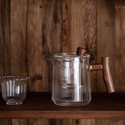 Teapot in glass with tea leaves unfurling in hot water