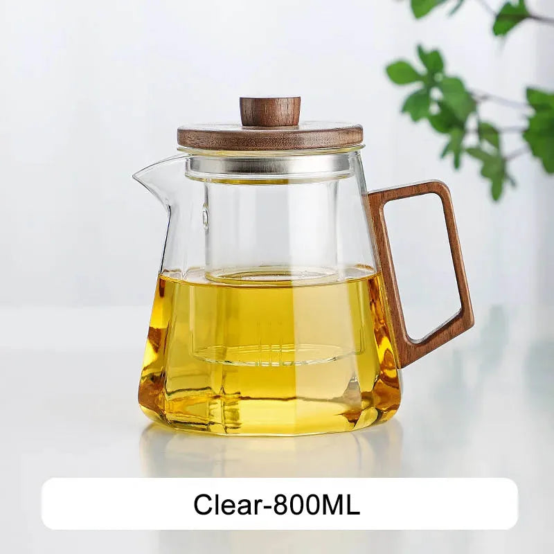 Scandinavian glass teapot pouring amber tea into a white ceramic cup