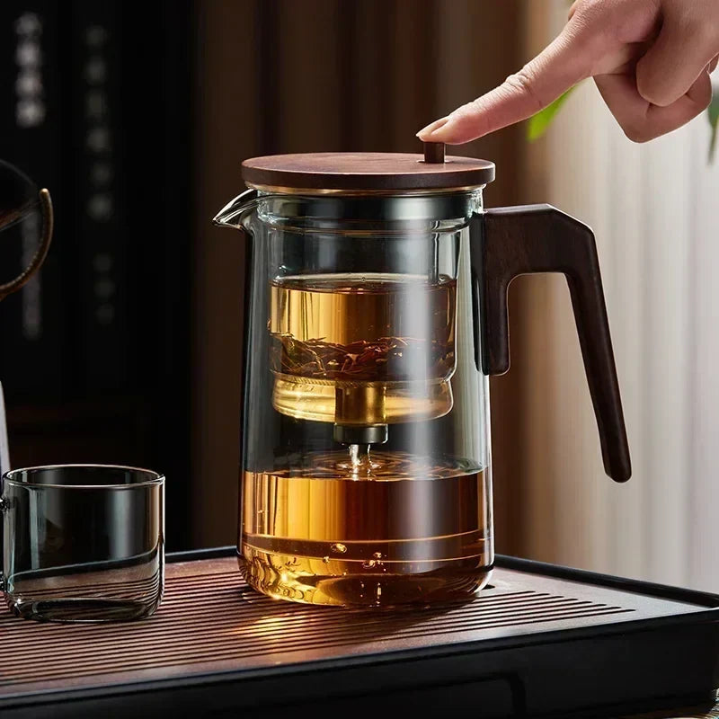 Scandinavian glass teapot pouring brewed loose-leaf tea into a cup