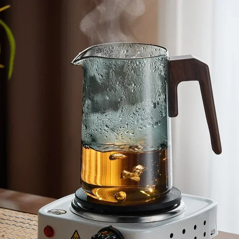 Glass teapot with tea leaves steeping and color developing in borosilicate body