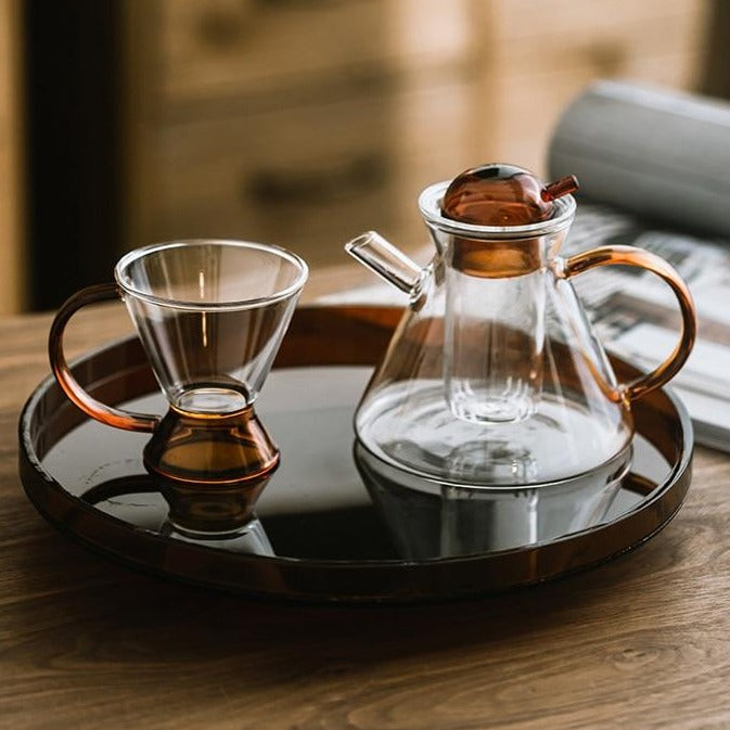 Pouring brewed tea from glass teapot with infuser into cup