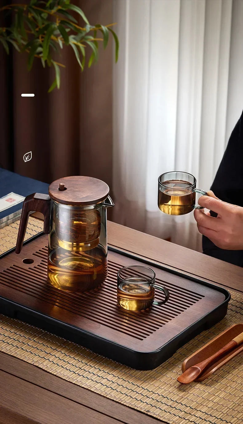 Glass teapot with candle warmer and cup set on a serving tray