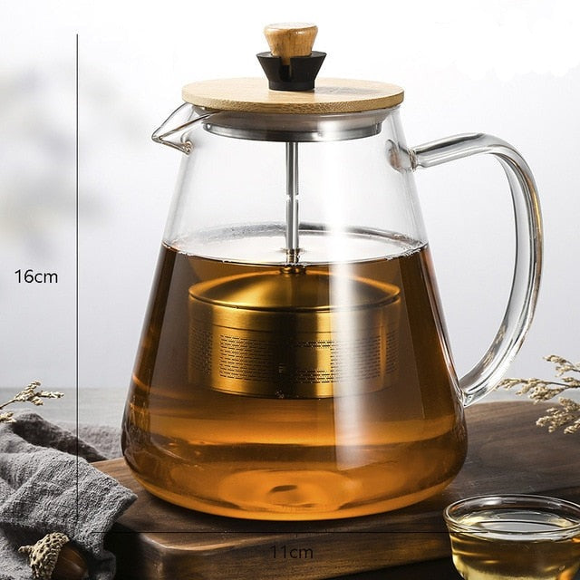 Scandinavian glass teapot pouring brewed tea into a cup, steady spout