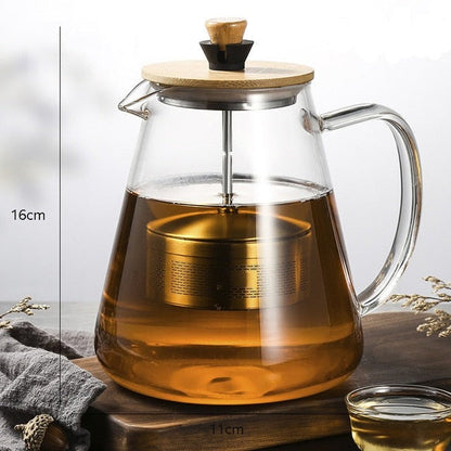 Scandinavian glass teapot pouring brewed tea into a cup, steady spout