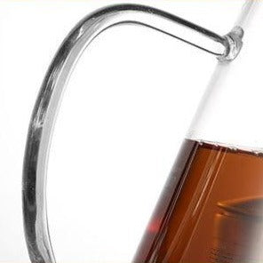Warm amber tea inside a clear glass teapot, light passing through