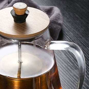 Glass teapot with lid removed showing stainless steel infuser inside