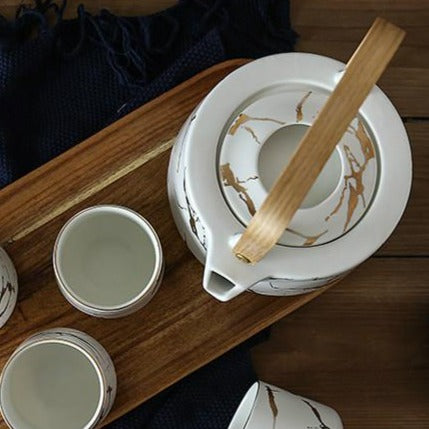 Nordic porcelain teapot 1L pouring tea into a white cup, gold handle detail visible