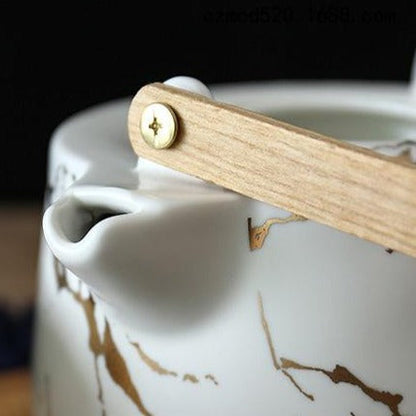 Close-up of Scandinavian porcelain teapot spout and gold-accent handle rim