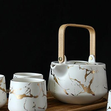 Nordic teapot 1L with a filled cup alongside, Black and Gold version, top-down view