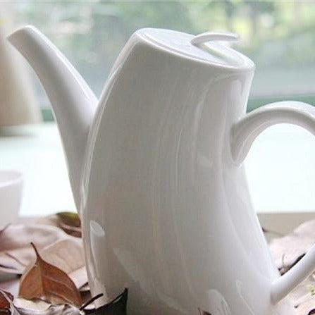 Porcelain teapot with cups on wooden table