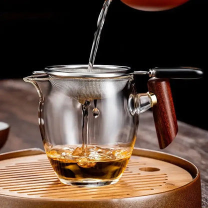 Silver tea strainer beside a freshly brewed cup of loose leaf tea