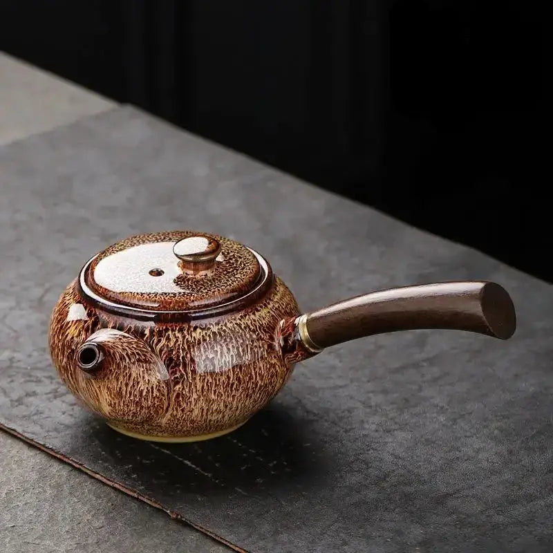 Brown small ceramic teapot with tea leaves nearby