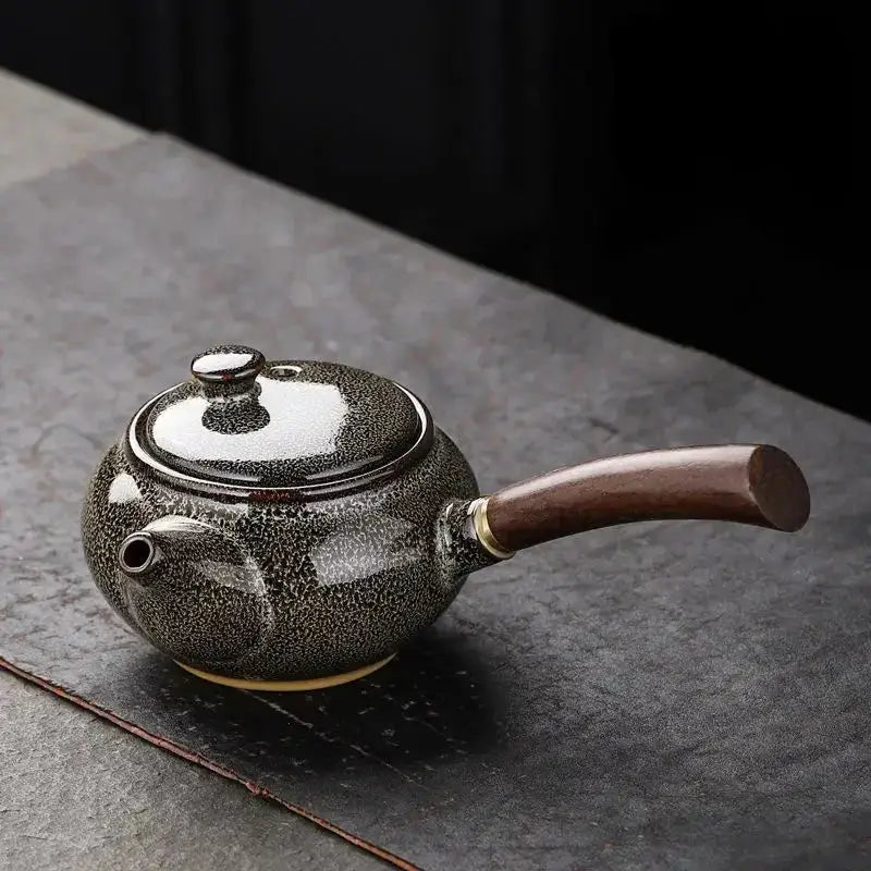 Black small ceramic teapot on dark background