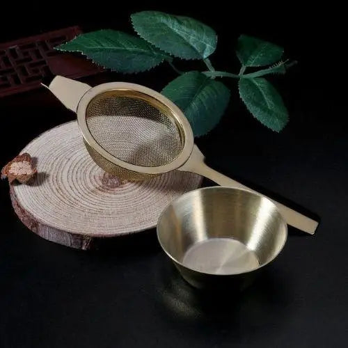 Stainless steel tea strainer resting on rim of ceramic mug in use