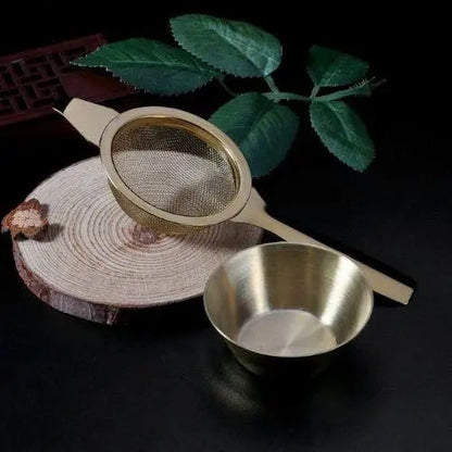 Stainless steel tea strainer resting on rim of ceramic mug in use