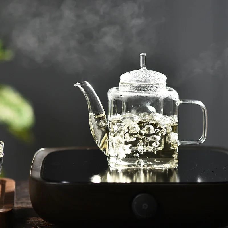Square glass teapot brewing white tea, clear body shows pale infusion