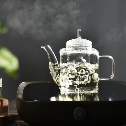 Square glass teapot brewing white tea, clear body shows pale infusion