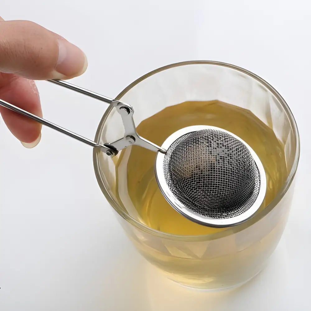 Stainless steel ball tea infuser steeping loose-leaf tea in a white mug